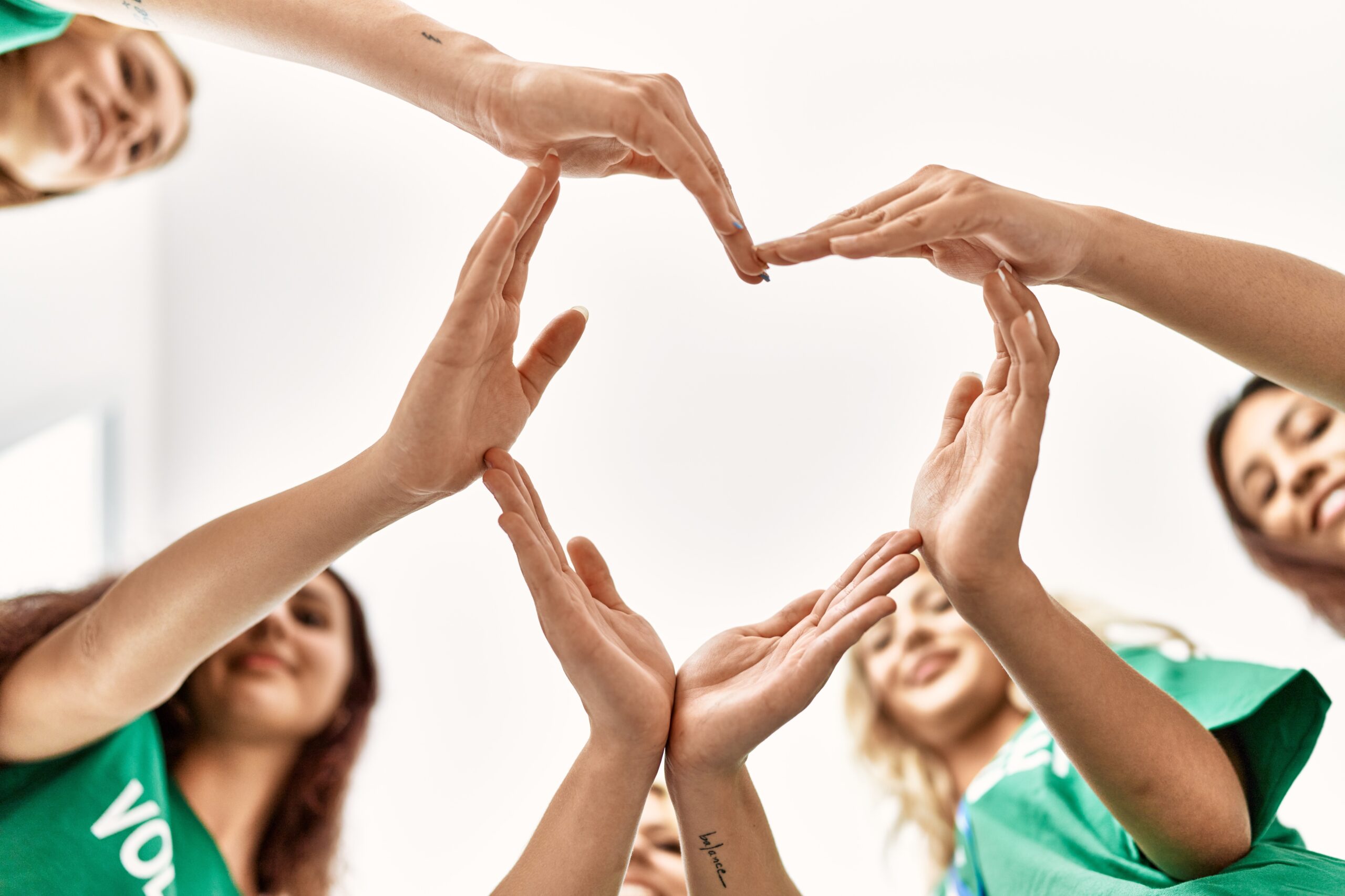 Group of young volunteers woman smiling happy make heart symbol with hands together to support those feeling hardship